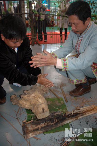 “冬交会”槟榔谷展区内，工作人员现场展示黎族人民古老的钻木取火工艺（13日摄）。上图中，两位工作人员轮流转动木棍。